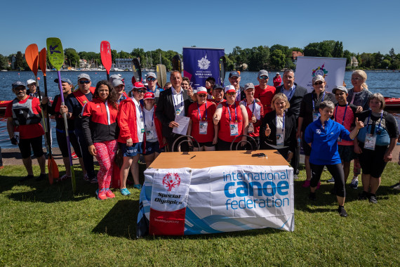 Von vielen fröhlichen Athlet*innen in Sportkleidung umgeben: Bettina Schilling (SOD / rechts), Lou Lauria (SOI /Mitte), John Edwards (ICF /
Mütze), Thomas Konietzko (ICF / links).